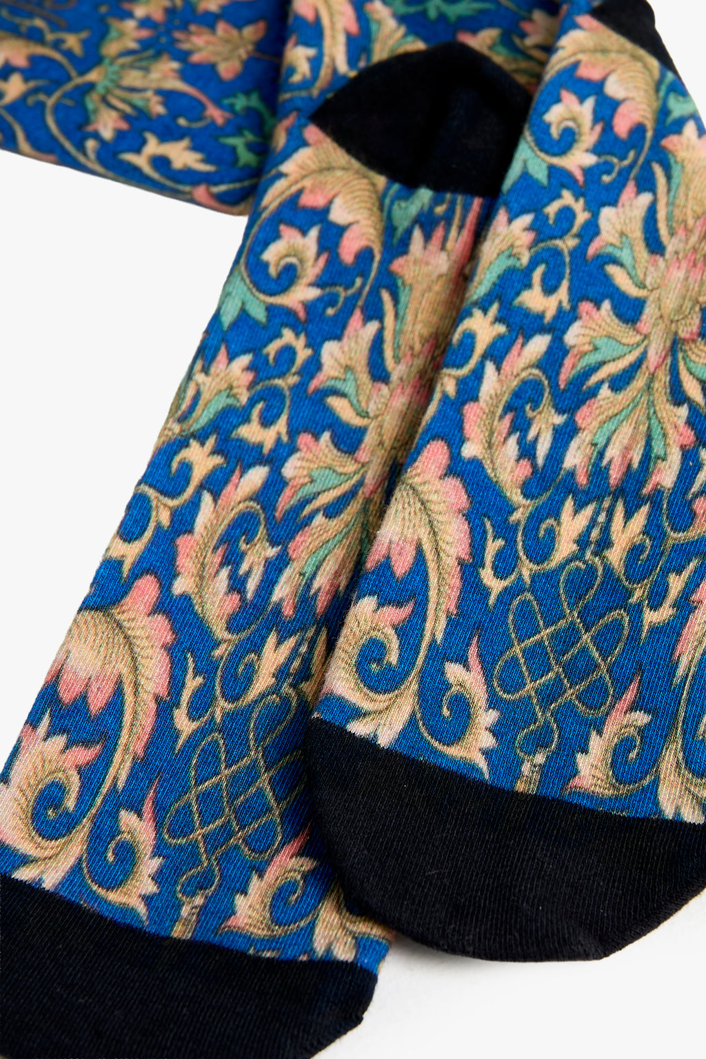 Close-up of a patterned fabric with blue, green, and pink colors on a white background.